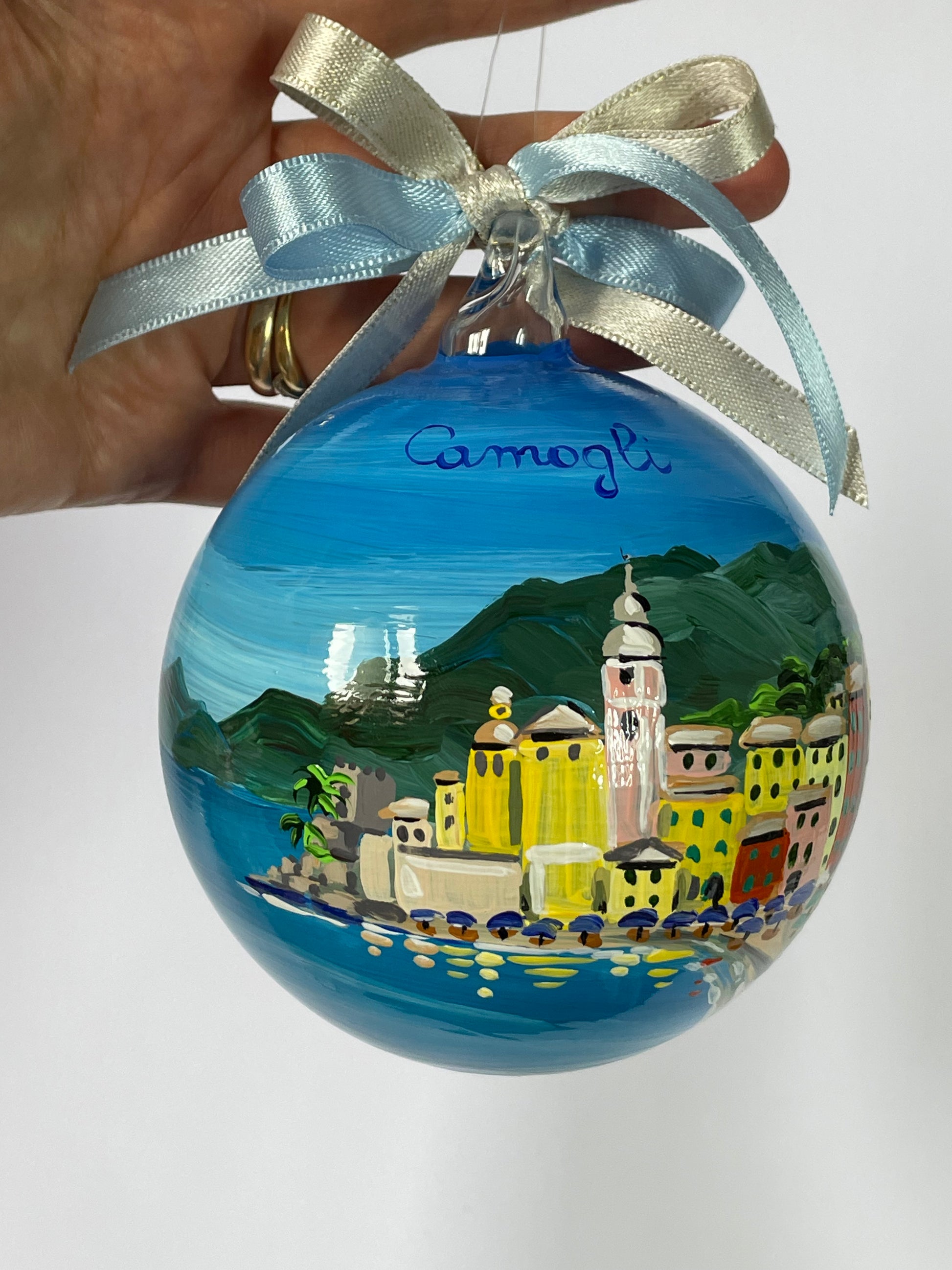 Ornamento in vetro dipinto a mano con Camogli, Liguria. E' raffigurato il borgo di case colorate affacciate sul mare, la spiaggia con gli ombrelloni 