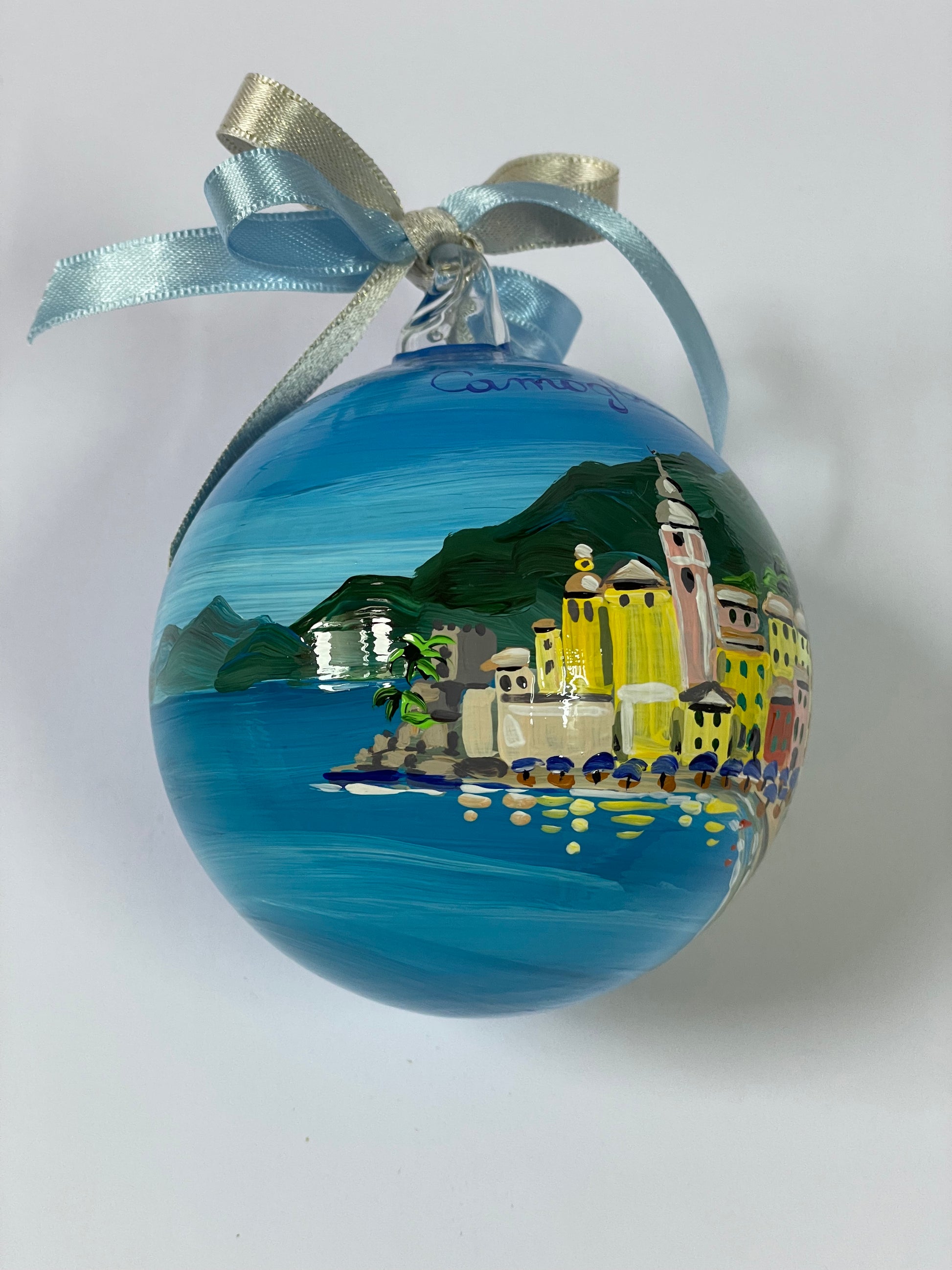 Ornamento in vetro dipinto a mano con Camogli, Liguria. E' raffigurato il borgo di case colorate affacciate sul mare, la spiaggia con gli ombrelloni 