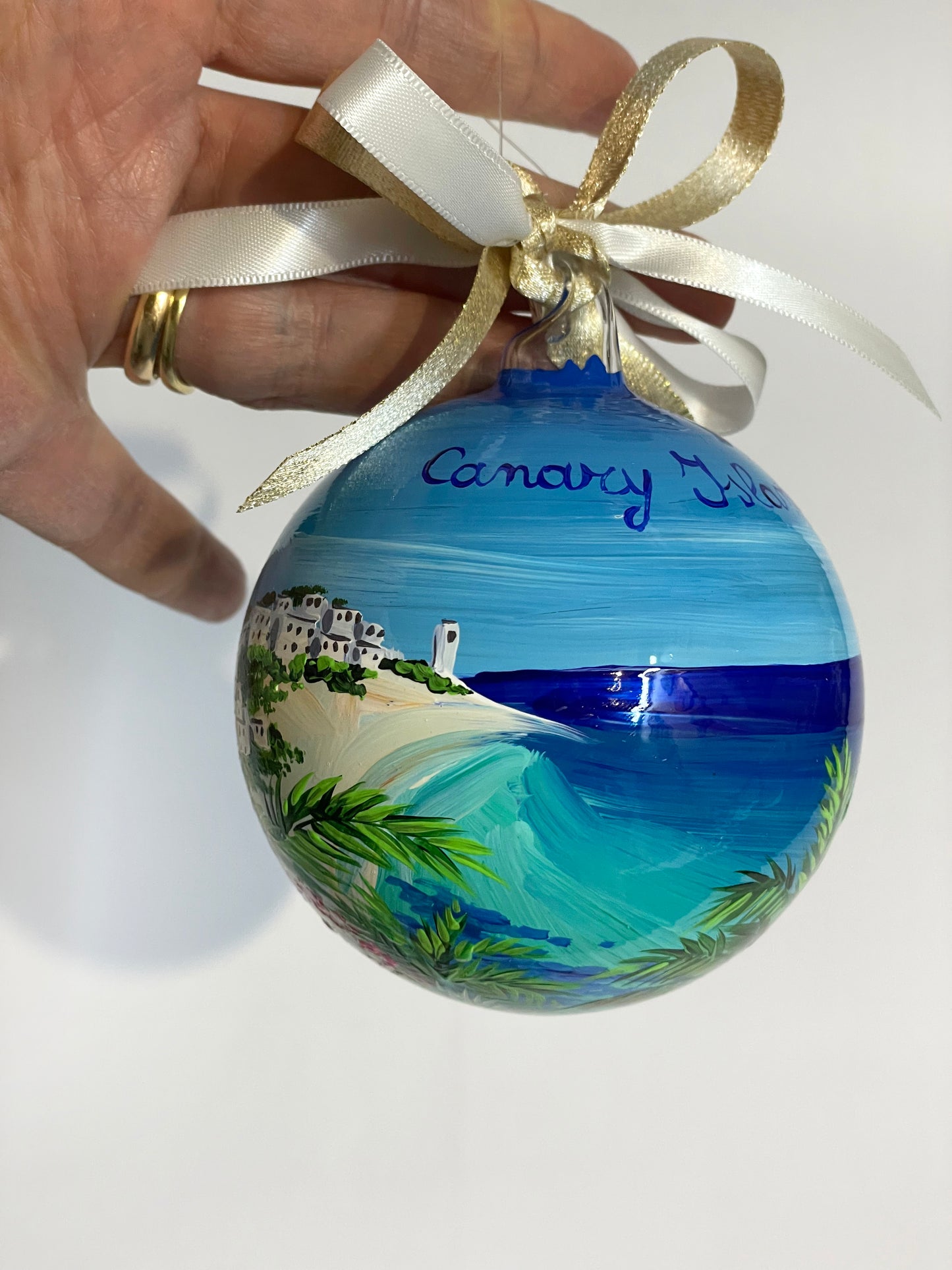 ornamento in vetro dipinto a mano, raffigura una spiaggia bianca delle Isole Canarie, palme e fiori e il mare cristallino.