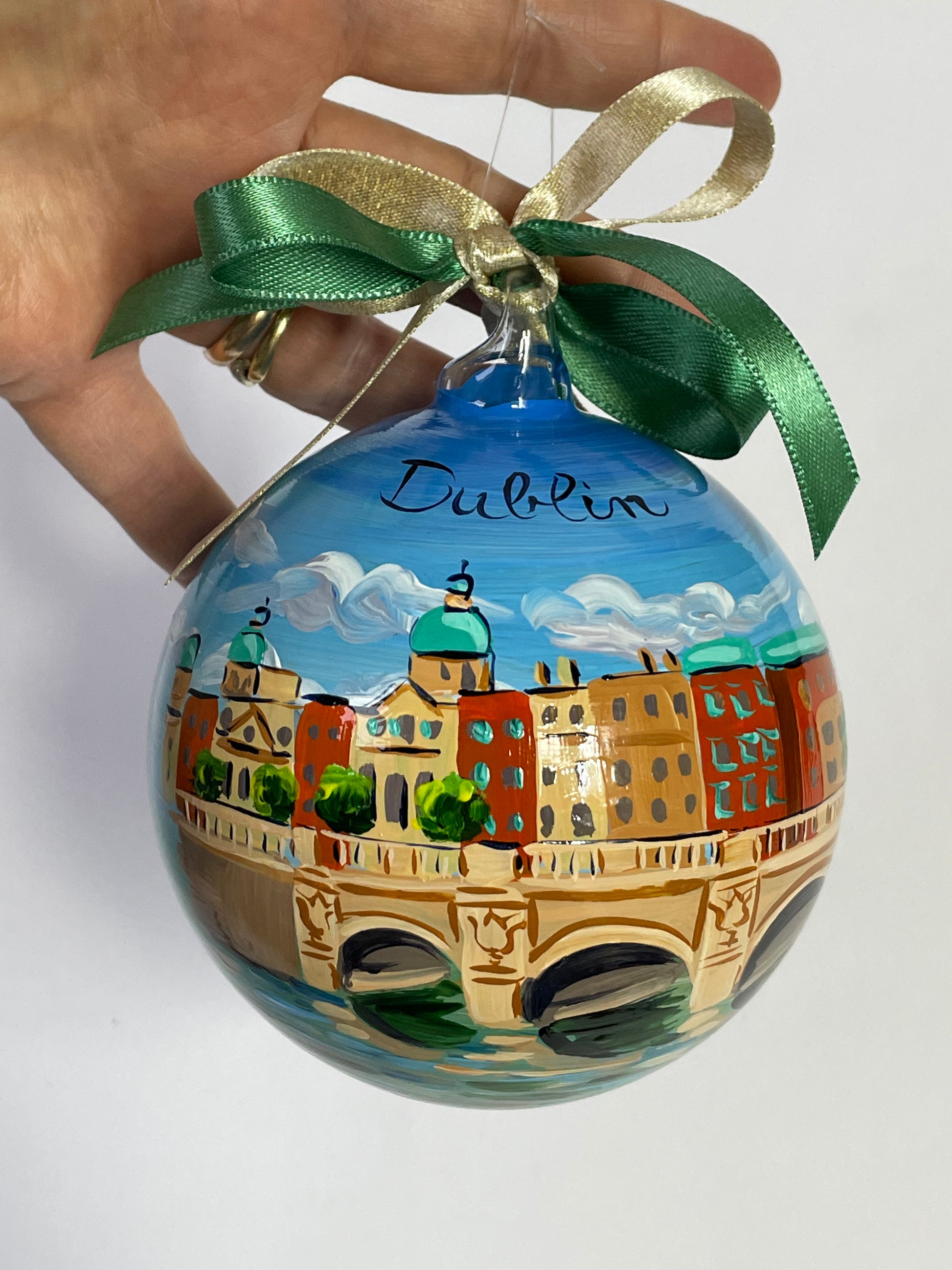 ornamento in vetro dipinto a mano con la città di Dublino, il cielo azzurro con nuvole bianche, un ponte sul fiume e gli edifici della città