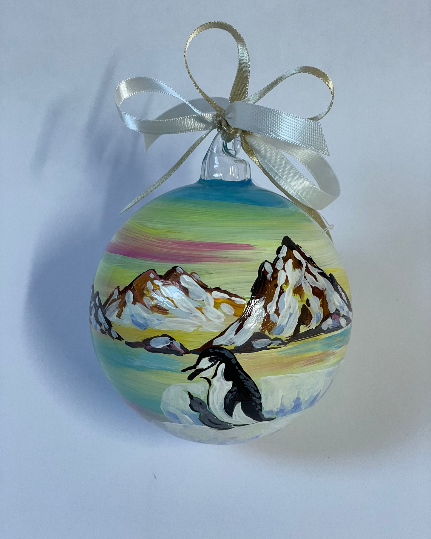 ornamento di vetro dipinto con paesaggio dell'Antartide con cielo sfumato azzurro rosa giallo e ghiaccio con due pinguini sopra