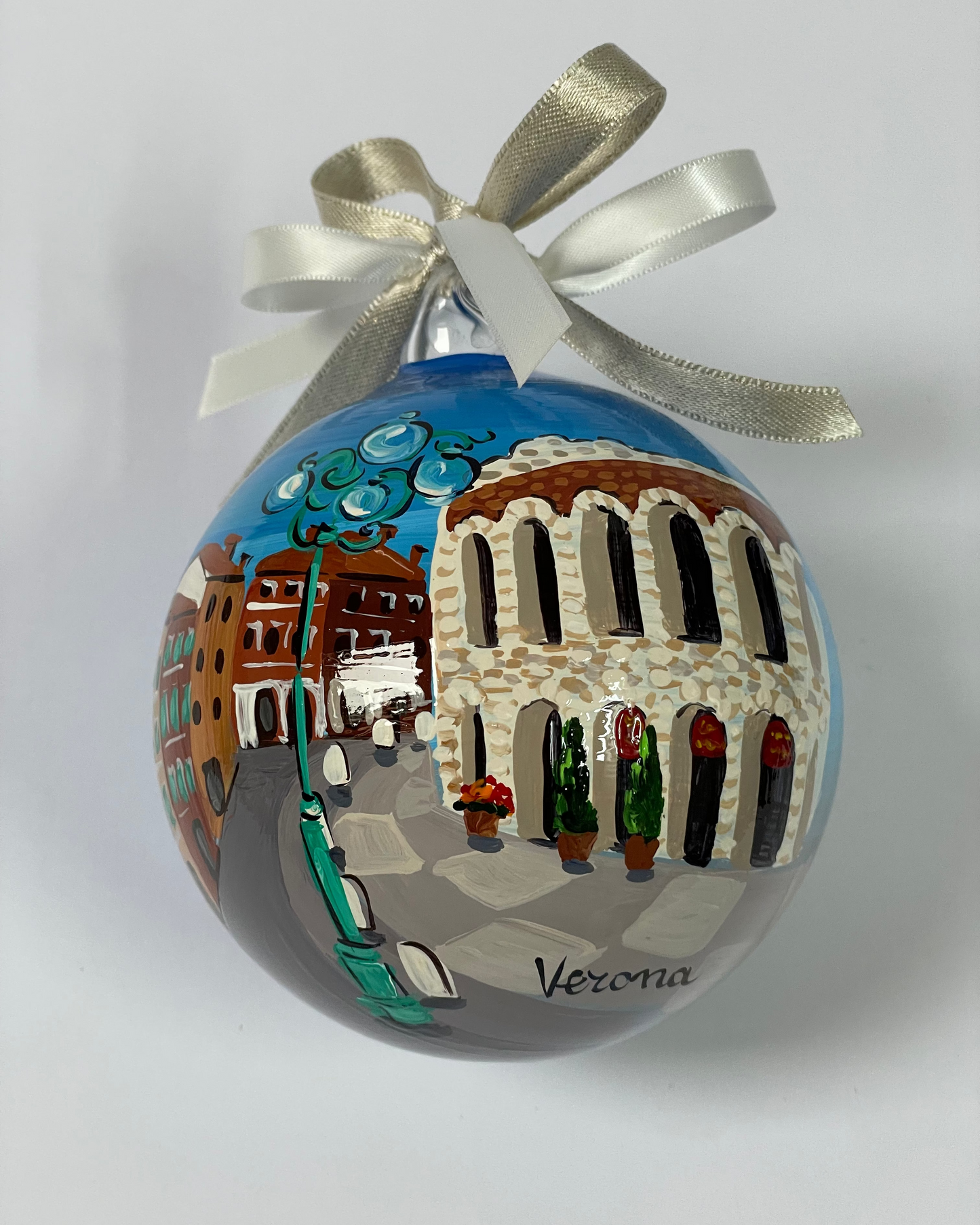 ornamento con la città di Verona. Il materiale è di vetro ed è dipinto a mano, il cielo è blu e si vede un viale ed una parte dell'arena di Verona.