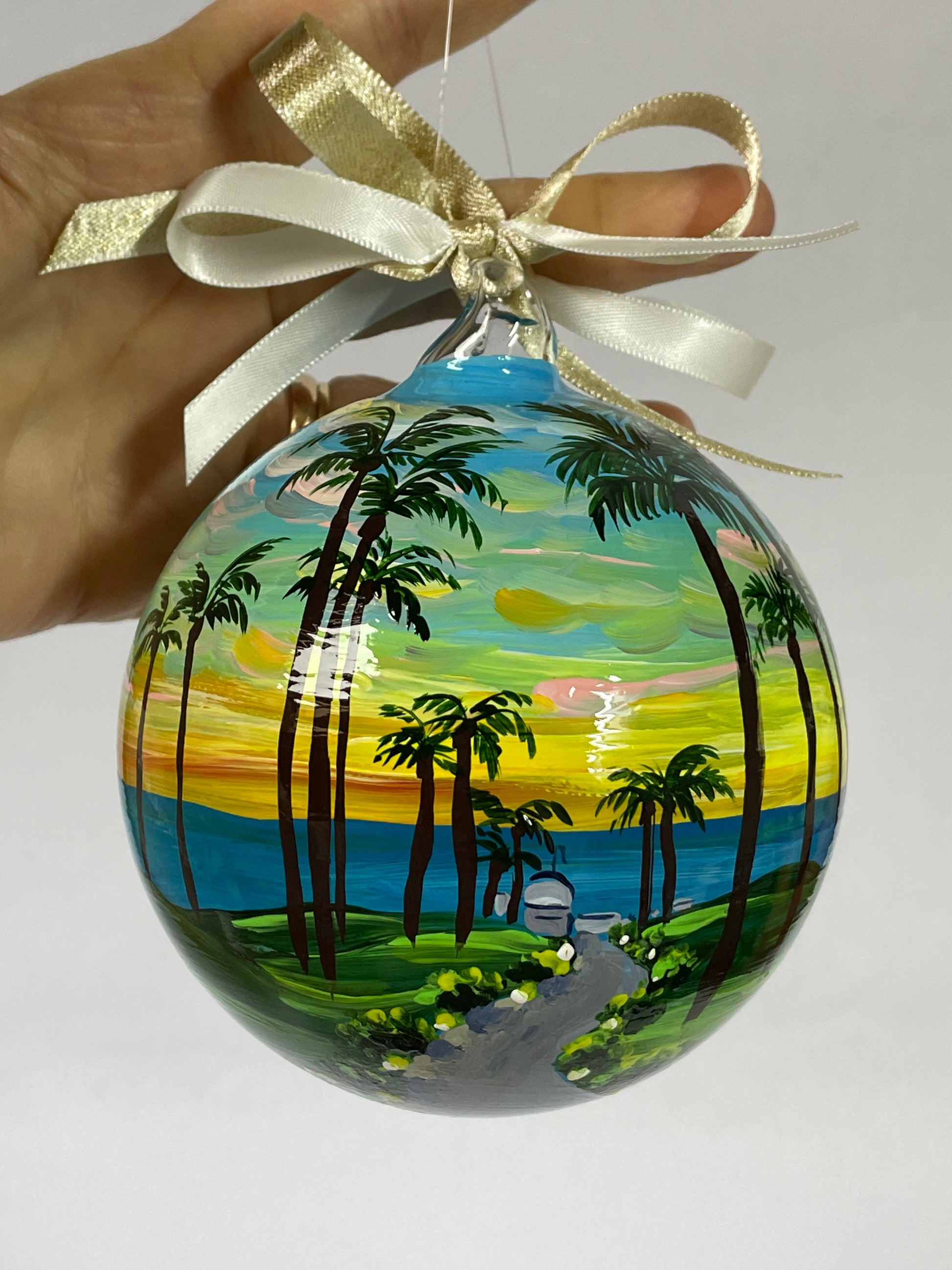 Hand-painted glass ornament held in hand – Maui Hawaii palm trees and ocean sunset landscape