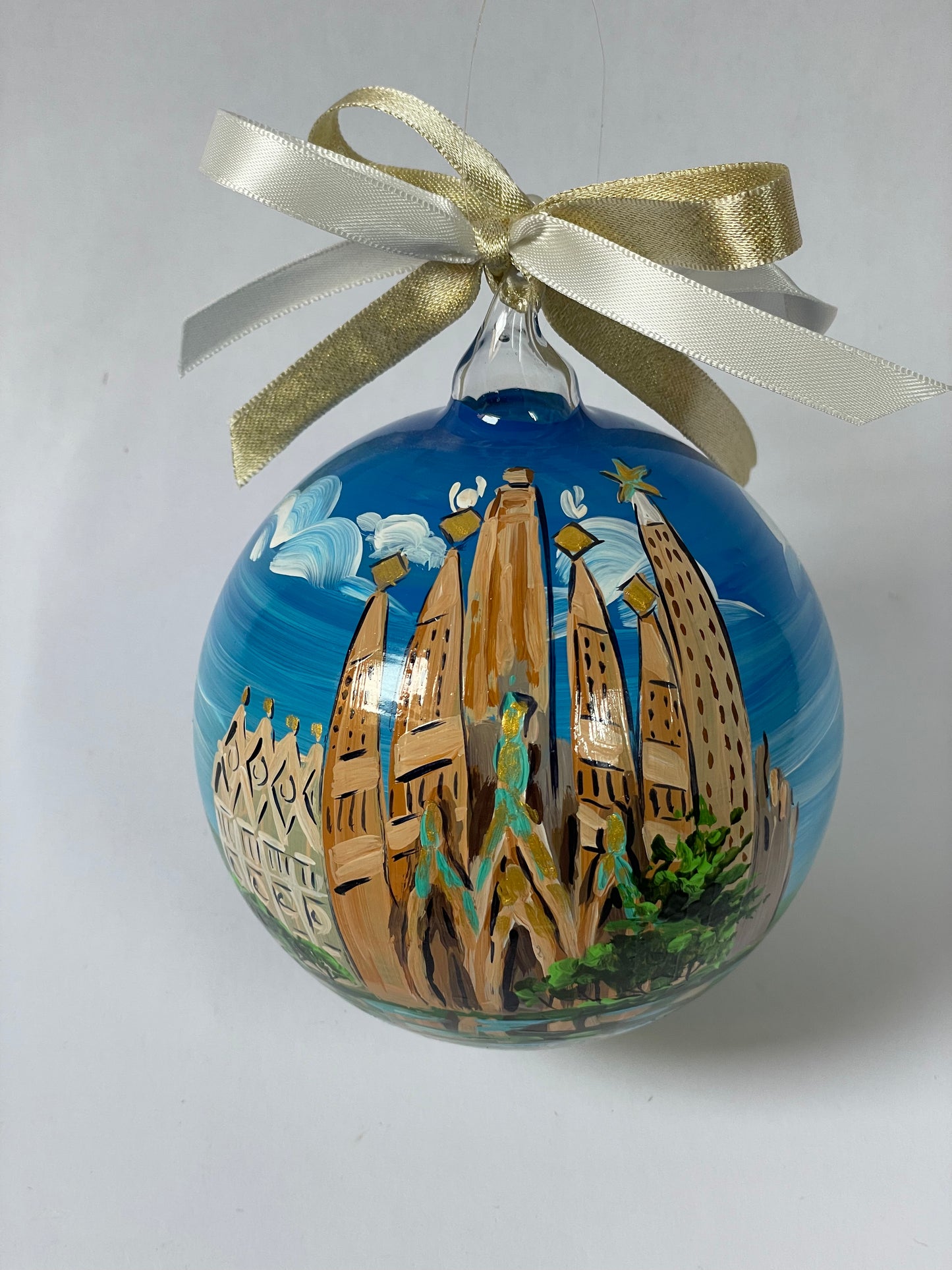 Angled view of hand-painted glass ornament – Sagrada Família golden spires with turquoise sculptures and blue sky