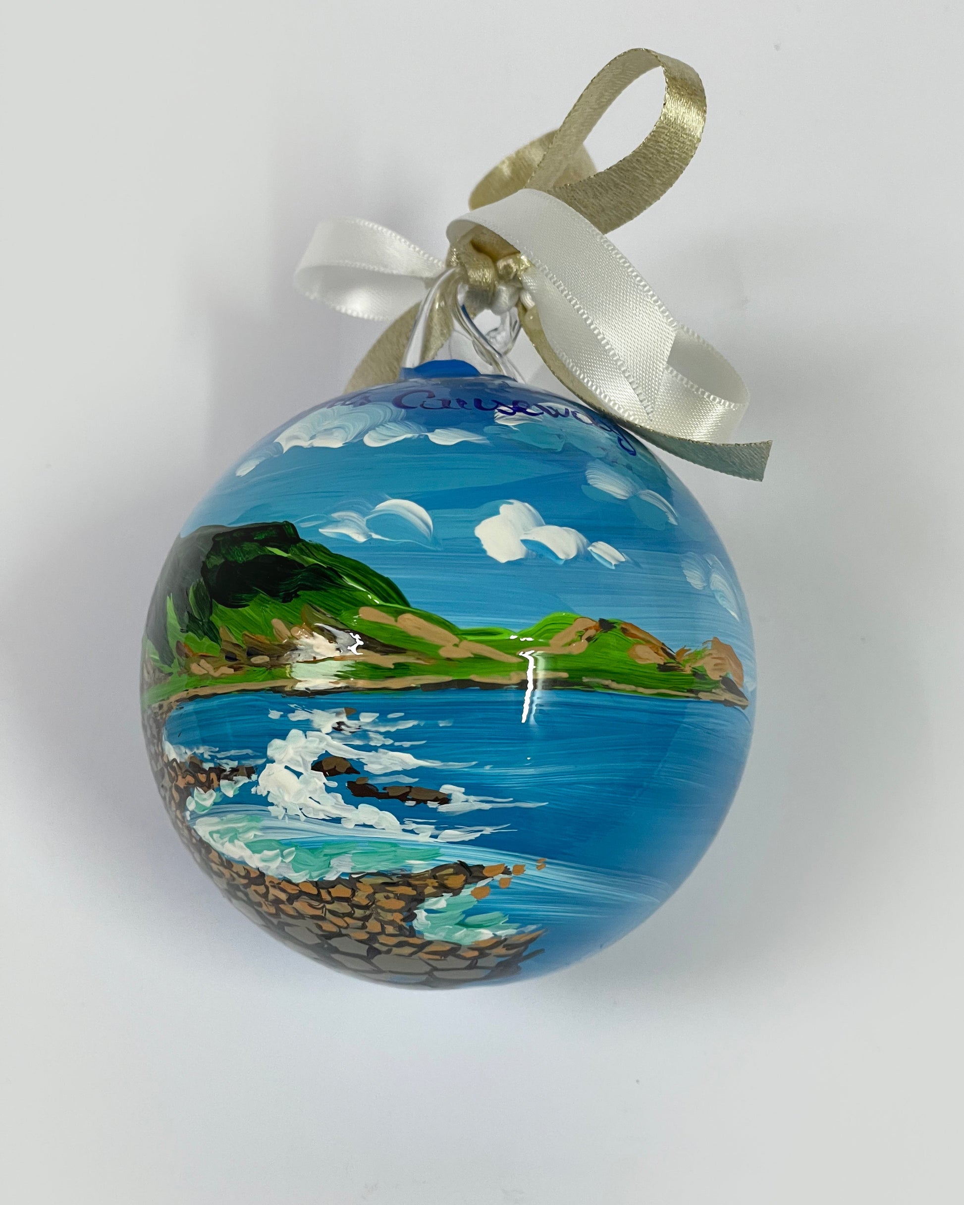 Ornamento in vetro dipinto a mano con Sentiero dei Giganti in Irlanda. mare, colline verdi e cielo azzurro con nuvole bianche.
