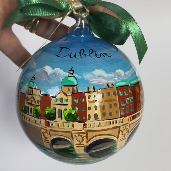 ornamento in vetro dipinto a mano con la città di Dublino, il cielo azzurro con nuvole bianche, un ponte sul fiume e gli edifici della città