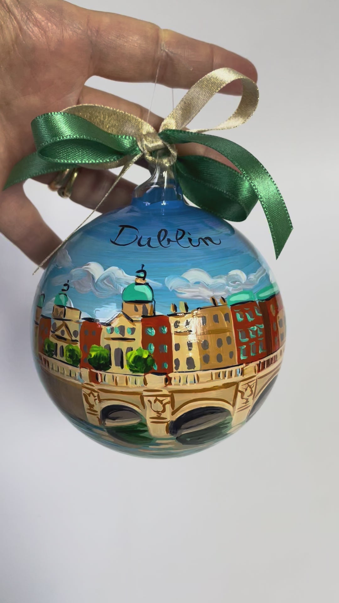 ornamento in vetro dipinto a mano con la città di Dublino, il cielo azzurro con nuvole bianche, un ponte sul fiume e gli edifici della città