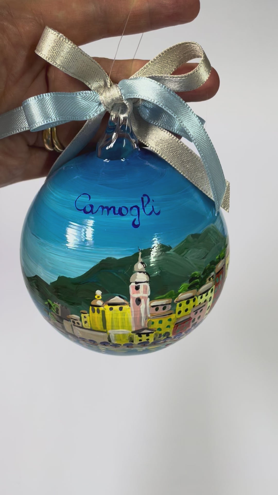 Ornamento in vetro dipinto a mano con Camogli, Liguria. E' raffigurato il borgo di case colorate affacciate sul mare, la spiaggia con gli ombrelloni 