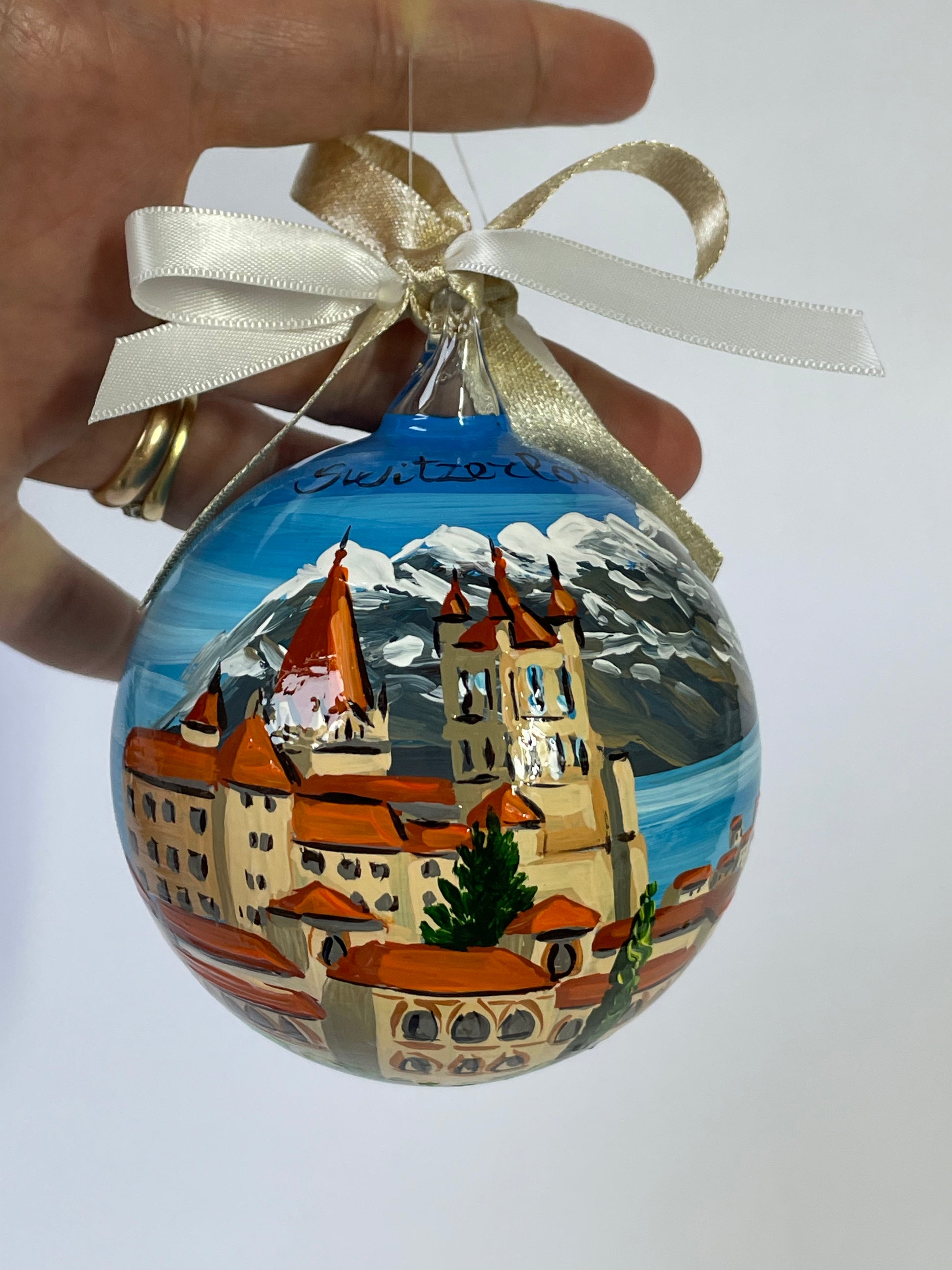 ornamento dipinto a mano con paesaggio della Svizzera con castello, lago e monti innevati